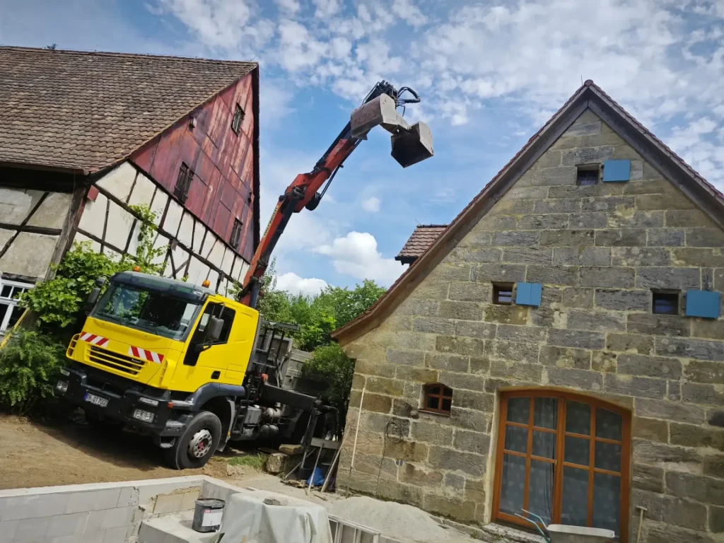 Gelber Lkw hebt last an Haus